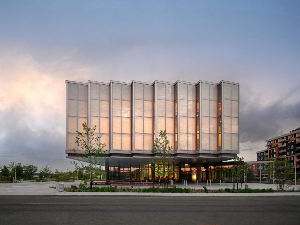 Vue extérieure du Pôle municipal de Vaudreuil‑Dorion, volume translucide au-dessus d’un socle vitré